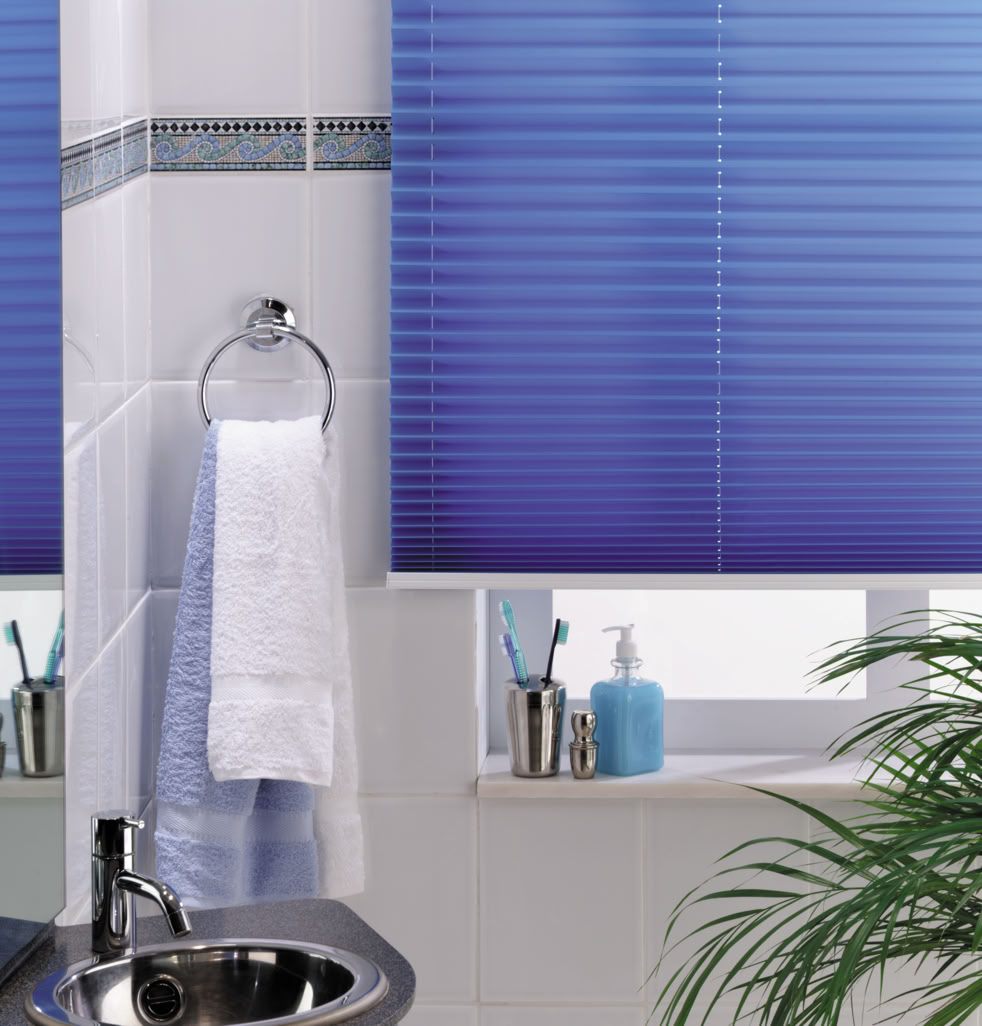 Badezimmer mit blauem Rollo, Handtuch an einem Halter, Waschbecken, Zahnbürstenhalter und Pflanze.