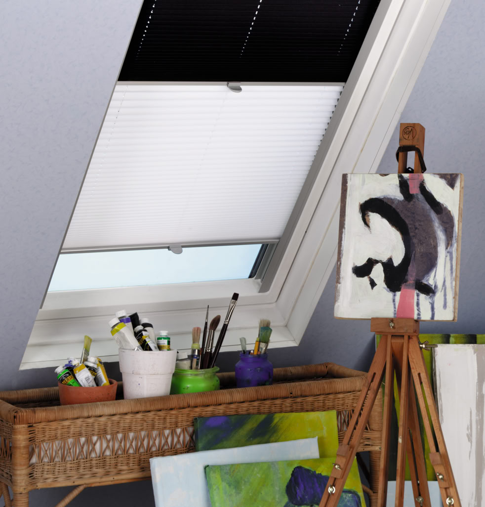 Ein Atelier mit einem Dachfenster, einer Staffelei mit einem abstrakten Gemälde, einem Tisch mit Malutensilien und mehreren Leinwänden.